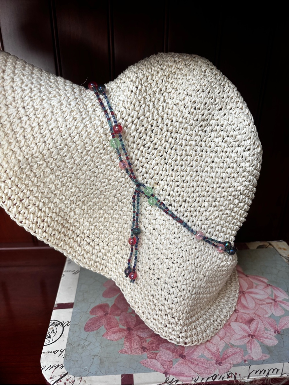 women's woven straw sun hat features a colorful beaded band and a floppy brim.